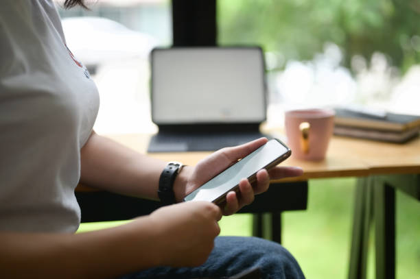 istock Cropped image of hands are using an empty screen smartphone at the wooden counter. 1266910012
