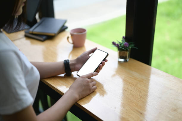 istock Cropped image of hands are using an empty screen smartphone at the wooden counter. 1266910035