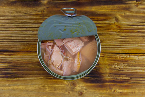 istock Open tin can of tuna fish on a wooden table. Top view 1266910268