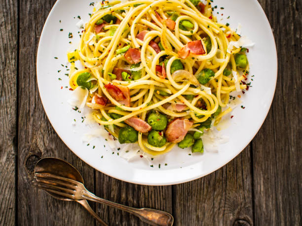 istock Spaghetti with bacon, broad bean and parmesan on wooden table 1266918832