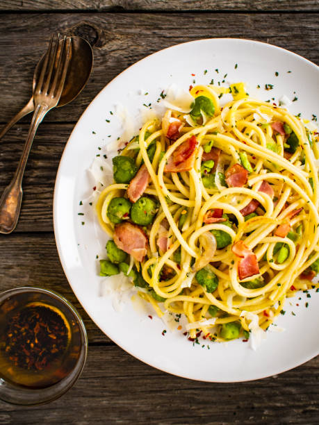 istock Spaghetti with bacon, broad bean and parmesan on wooden table 1266918874