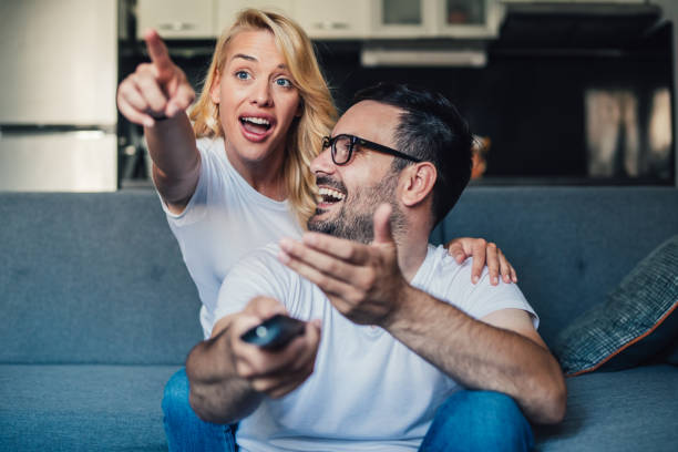 istock Cute young couple cuddling while watching tv. 1266919011