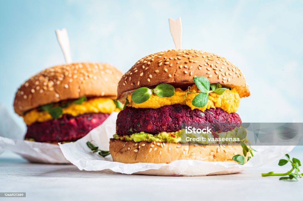 Vegan beetroot burger with sweet potato sauce and guacamole. Plant based diet concept. Vegan burger with beetroot cutlet, sweet potato sauce and guacamole. Vegan Food Stock Photo