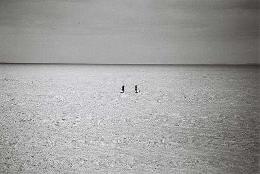 Two paddleboarders on sunlit seas, black and white 35mm
