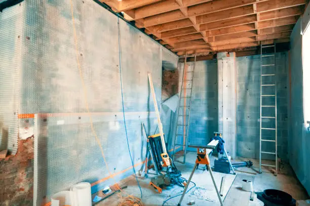 Plastic membrane is applied to the walls of a basement, collecting water which falls down and is extracted via a drainage system, and damproofing the room.