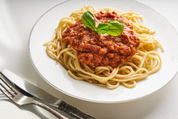 Traditional pasta bolognese served on a white plate and garnished with basil stock photo