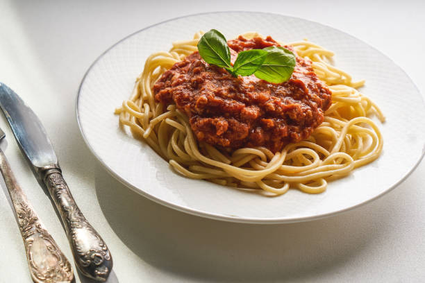 istock Traditional pasta bolognese served on a white plate and garnished with basil 1266923133