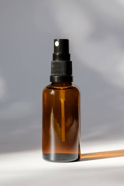 bouteille en verre d’ambre cosmétique avec pulvérisateur sur le fond blanc. conception organique naturelle d’emballage de parfum - amber bottle photos et images de collection