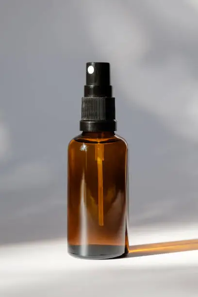 Photo of Cosmetic amber glass bottle with sprayer on white background. Natural organic perfume packaging design