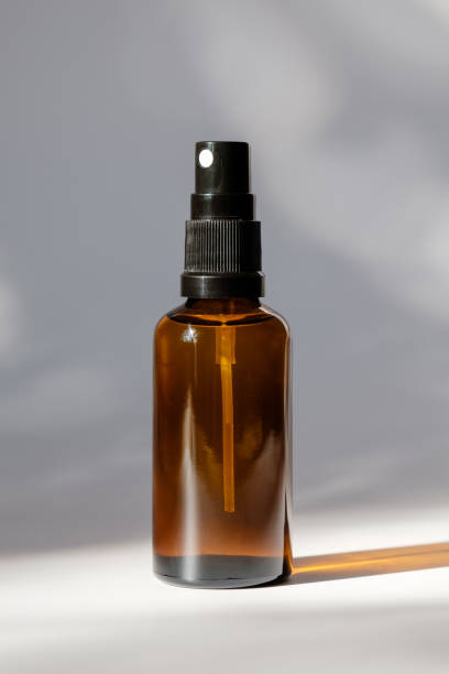 garrafa de vidro âmbar cosmético com pulverizador no fundo branco. design de embalagem de perfume orgânico natural - amber bottle - fotografias e filmes do acervo