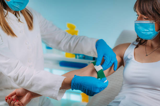 preparazione per la procedura di flebotomia, paziente donna e infermiera medica che indossa maschere protettive - bloodwork foto e immagini stock