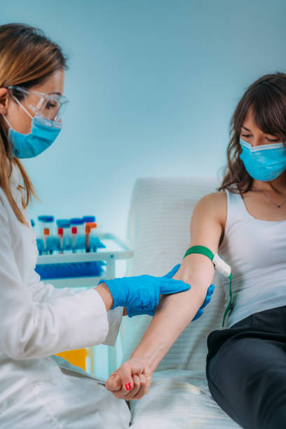 preparazione per la procedura di flebotomia, paziente donna e infermiera medica che indossa maschere protettive - bloodwork foto e immagini stock