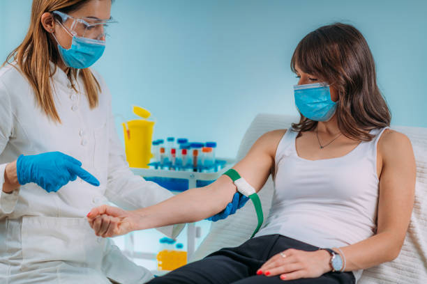 preparazione per la procedura di flebotomia, paziente donna e infermiera medica che indossa maschere protettive - bloodwork foto e immagini stock