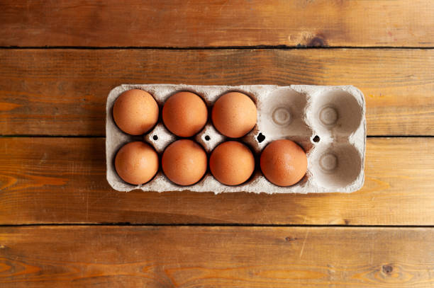 istock brown eggs in a cardboard box with empty cells on a brown wooden table, top view 1266932439