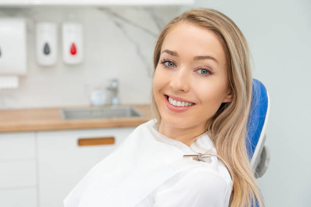 young woman sitting on chair at dentist office - dentist office dentists chair dental equipment white imagens e fotografias de stock