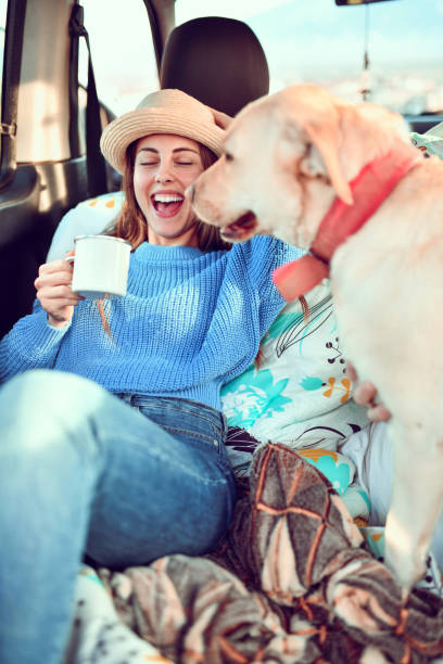 istock Female Drinking Tea And Playing With Dog In Minivan 1266934142