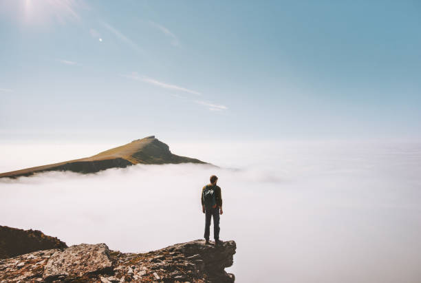 istock Man explorer standing alone on cliff edge mountain over clouds active travel adventure lifestyle vacations outdoor in Norway 1266936390