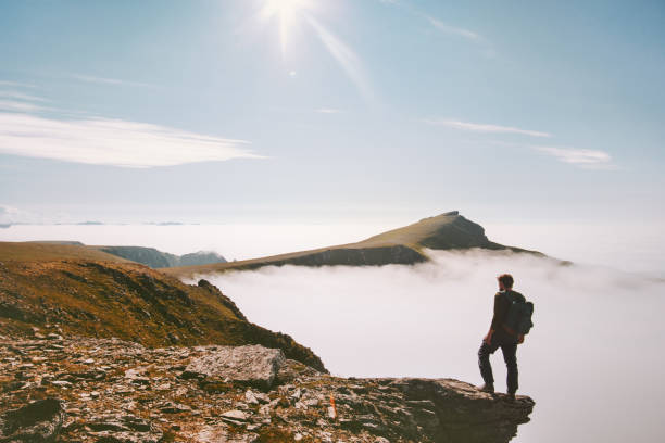 istock Traveler man hiking alone in mountains over clouds enjoying view active summer vacations trip adventure travel lifestyle outdoor 1266936482