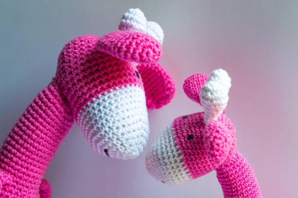 Two pastel pink crochet giraffe dolls embraced
