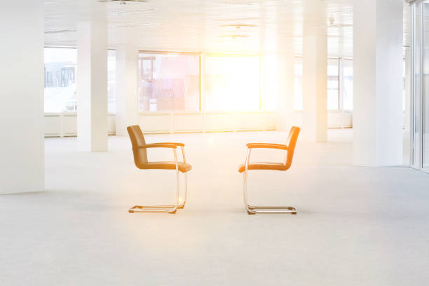 istock Two chairs in an empty office with sun shining in background 1266937660