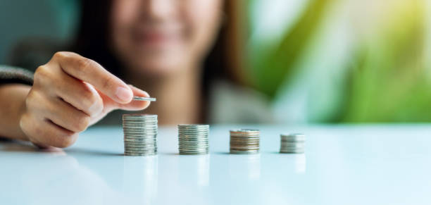 istock Businesswoman holding and stacking coins 1266939544