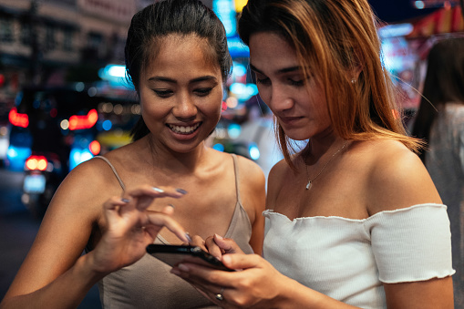 Two smiling women enjoying a girls night out, outside Chinatown Bangkok
