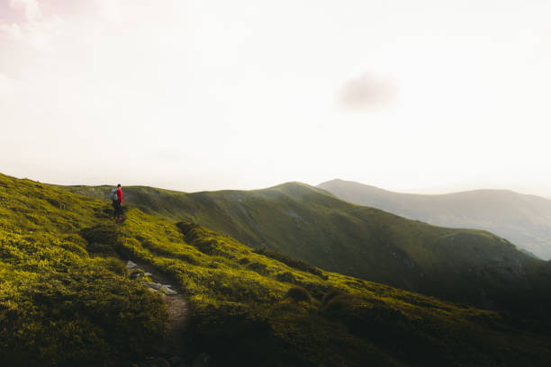 istock Man backpacker having the best time outdoors hiking in the mountains during sunset 1266946725