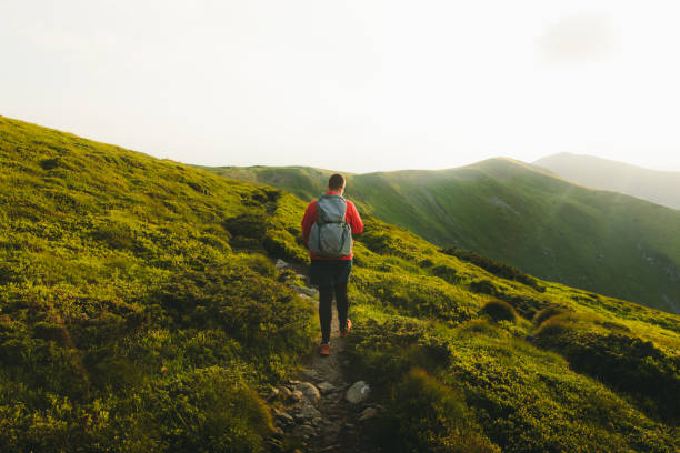 istock Man backpacker having the best time outdoors hiking in the mountains during sunset 1266947743
