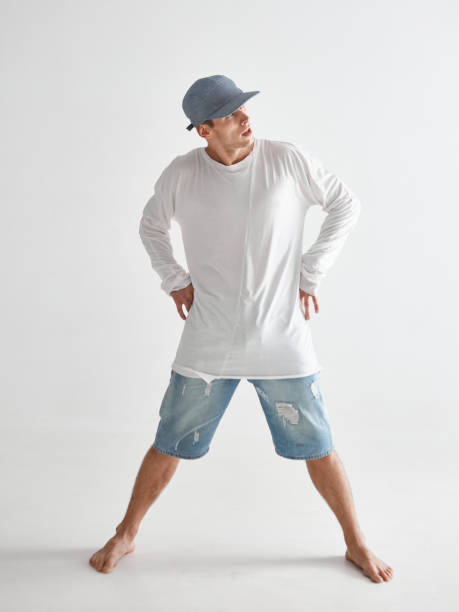 istock Stylish young guy breakdancer in cap barefoot standing in studio isolated on white background. Dance school poster 1266948244
