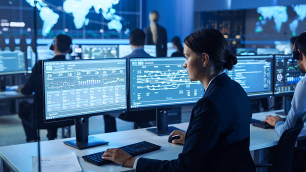 istock Confident Female Data Scientist Works on Personal Computer Wearing a Headset in Big Infrastructure Control and Monitoring Room. Woman Engineer in a Call Center Office Room with Colleagues. 1266953115