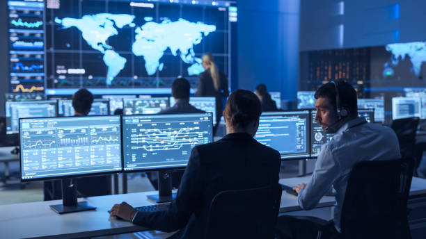 istock Team of Professional Computer Data Science Engineers Work on Desktops with Screens Showing Charts, Graphs, Infographics, Technical Business Data and Statistics. Low Key Control and Monitoring Room. 1266953129