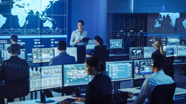 istock Team of Professional Computer Data Science Engineers Work on Desktops with Screens Showing Charts, Graphs, Infographics, Technical Neural Data and Statistics. Dark Control and Monitoring Room. 1266953141