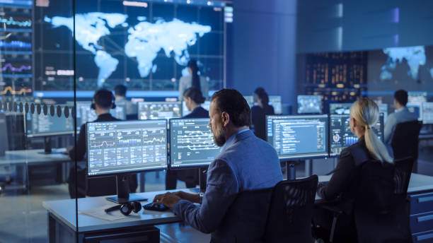 istock Team of Professional Computer Data Science Engineers Work on Desktops with Screens Showing Charts, Graphs, Infographics, Technical Neural Data and Statistics. Low Key Control and Monitoring Room. 1266953149