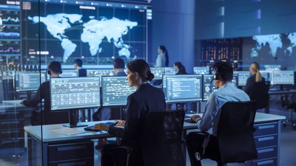 istock Team of Professional Computer Data Science Engineers Work on Desktops with Screens Showing Charts, Graphs, Infographics, Technical Neural Data and Statistics. Low Key Control and Monitoring Room. 1266953170