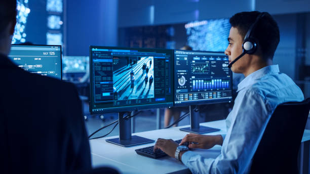 istock Confident Male Data Scientist Works on Personal Computer Wearing a Headset in Big Infrastructure Control and Monitoring Room. Surveillance Tracking Shot of People Walking on City Streets 1266953230