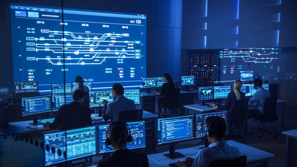 istock Team of Professional Computer Data Science Engineers Work on Desktops with Screens Showing Charts, Graphs, Infographics, Technical Neural Data and Statistics. Low Key Control and Monitoring Room. 1266953253