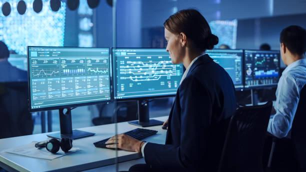 istock Confident Female Data Scientist Works Closely to her Young Colleague in Big Control and Monitoring Room with Neural Network. Young Specialists Talk and Discuss Work in a Room with Other Employees. 1266953255
