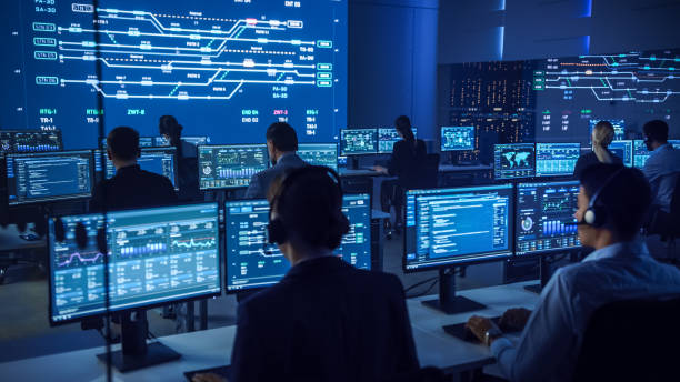 istock Team of Professional Computer Data Science Engineers Work on Desktops with Screens Showing Charts, Graphs, Infographics, Technical Neural Data and Statistics. Low Key Control and Monitoring Room. 1266953355
