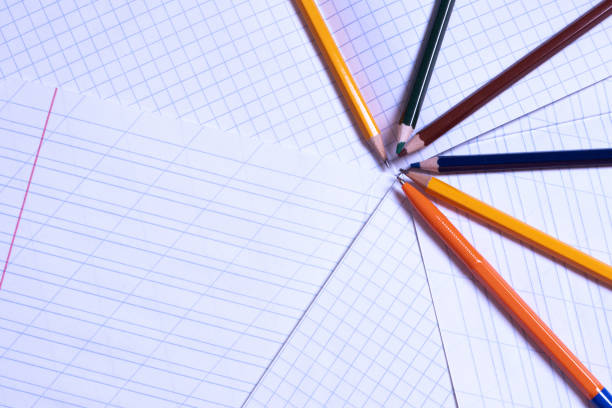 istock Top view of blank sheets of a squared notebook in a line and colored pencils. Flat lay, copy space 1266954568