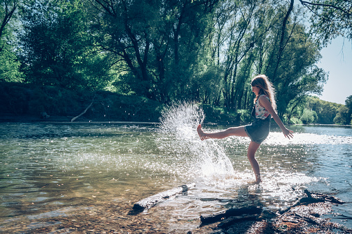 adorable blond girl playing with water in shallow water in sunny summer day