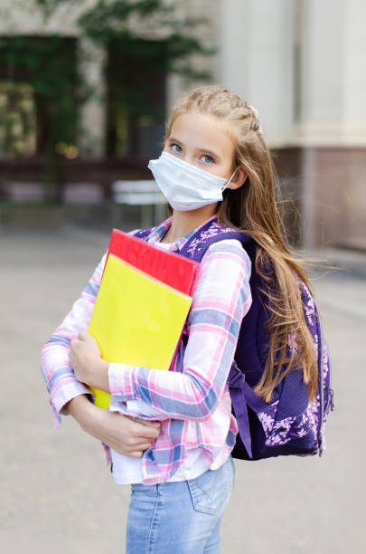 フェイスマスクと消毒剤を持つ小さな女の子の子供。教育コンセプト。居心地の良い19の後に学校に戻る - 3119 ストックフォトと画像