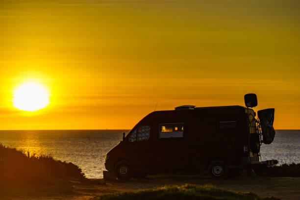 istock Camper van on beach at sunrise 1266957107
