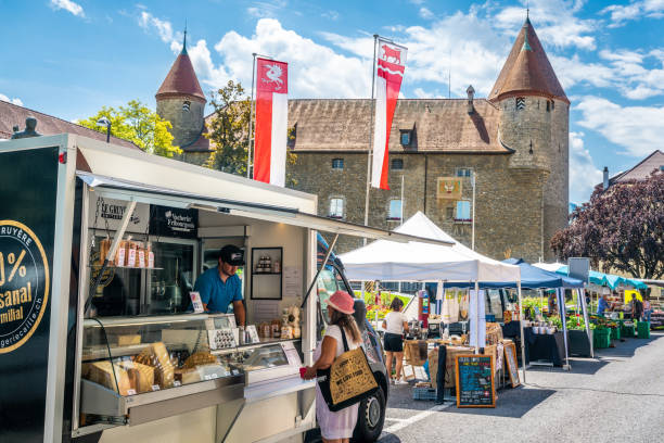 Le Gruyere AOP cheese shop at Bulle market with people and castle in background in Bulle La Gruyere Switzerland Bulle Switzerland , 27 June 2020 : Le Gruyere AOP cheese shop at Bulle market with people and castle in background in Bulle La Gruyere Switzerland bulle stock pictures, royalty-free photos & images