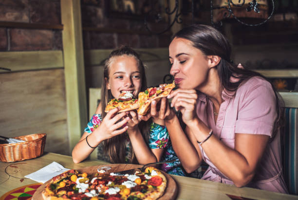 portrait of happy family eating in the restaurant - pizzeria imagens e fotografias de stock