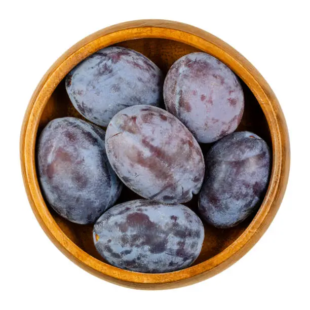 Photo of Zwetschge. Fresh and ripe European plums in a wooden bowl.