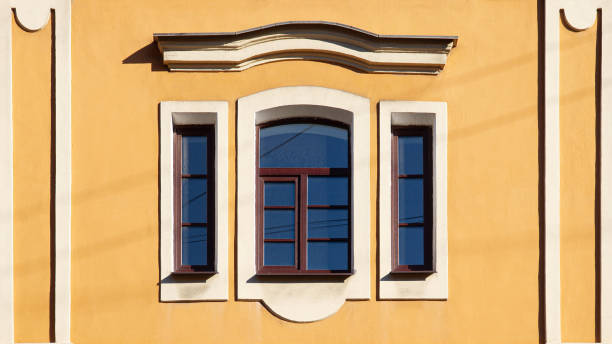 istock brown old three windows in white frame and pediment on yellow wall 1266963547