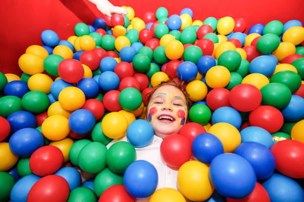Cheerful kid playing in ball pool, feeling very happy.