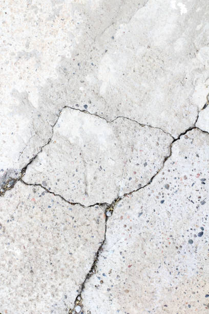 istock Concrete surface with cracks without painting with clearly visible pebbles of different sizes as a background 1266969572