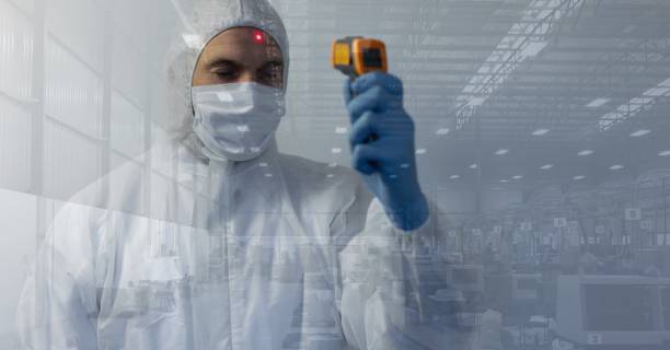 istock Healthcare worker wearing protective suit and using thermometer gun on himself with materials in bac 1266971011