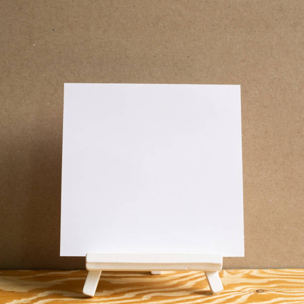istock White easel with blank canvas on wooden desk with brown background 1266971237